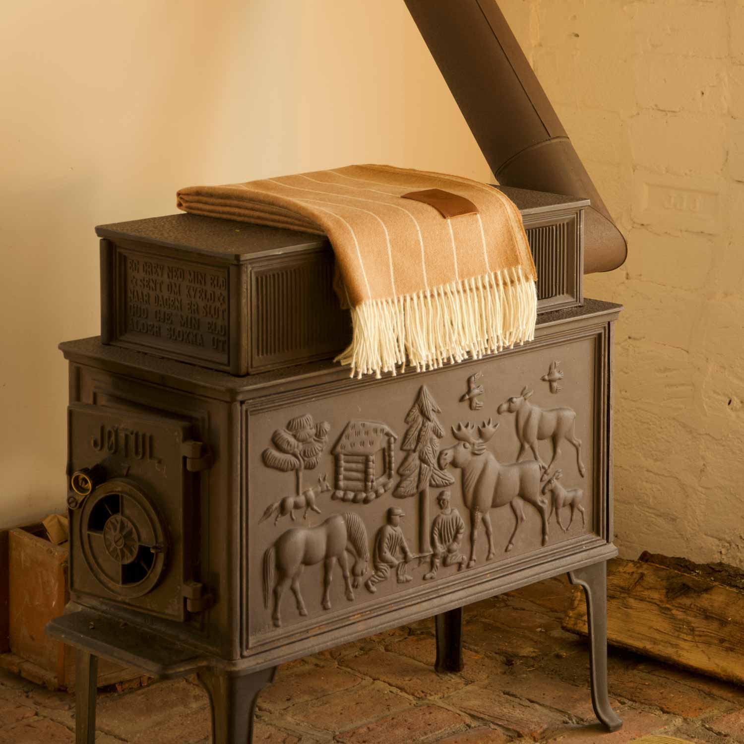 A brown and cream striped alpaca blanket, draped over an old iron stove