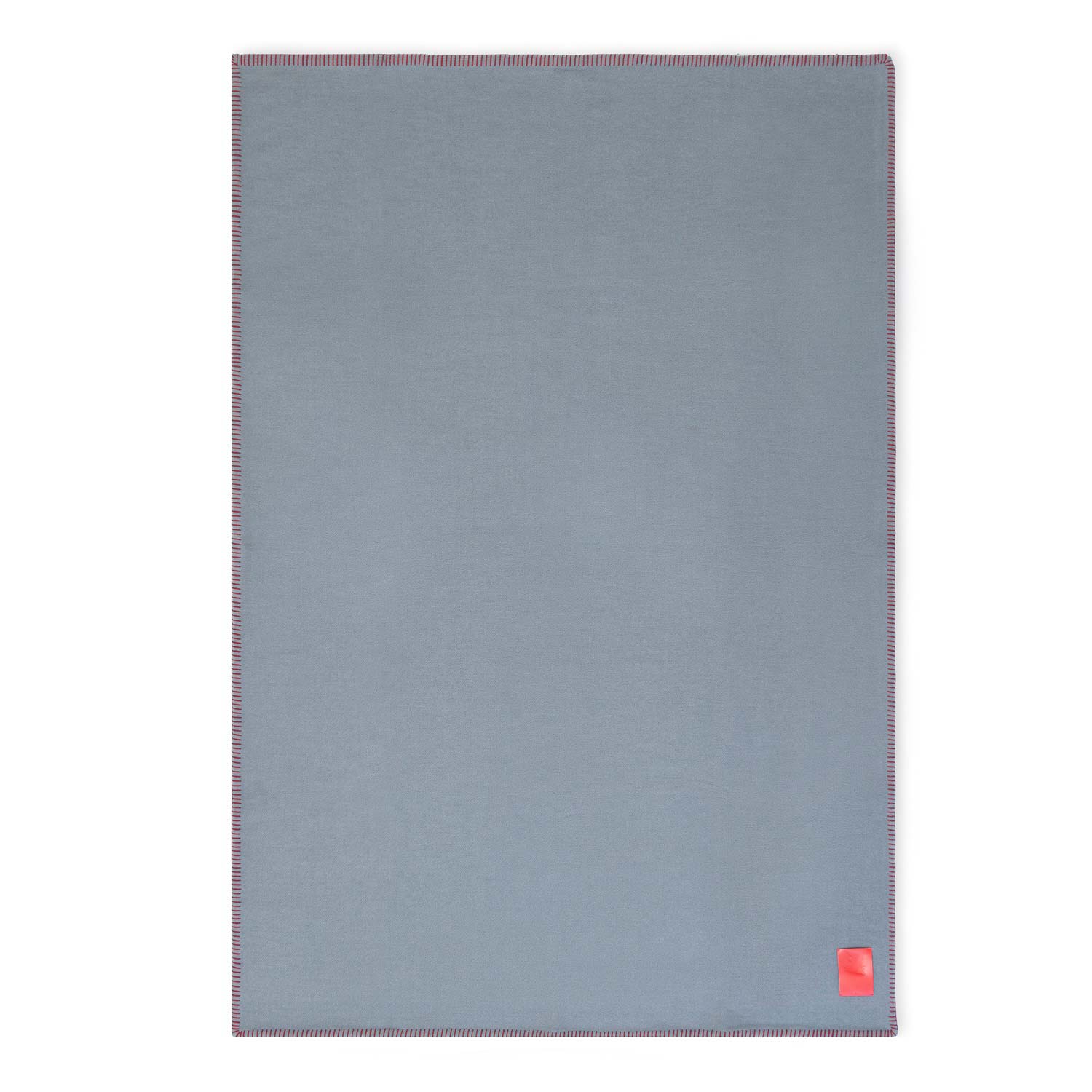 A flat gray merino wool blanket with red contrast stitching and a red tag visible on the lower side.