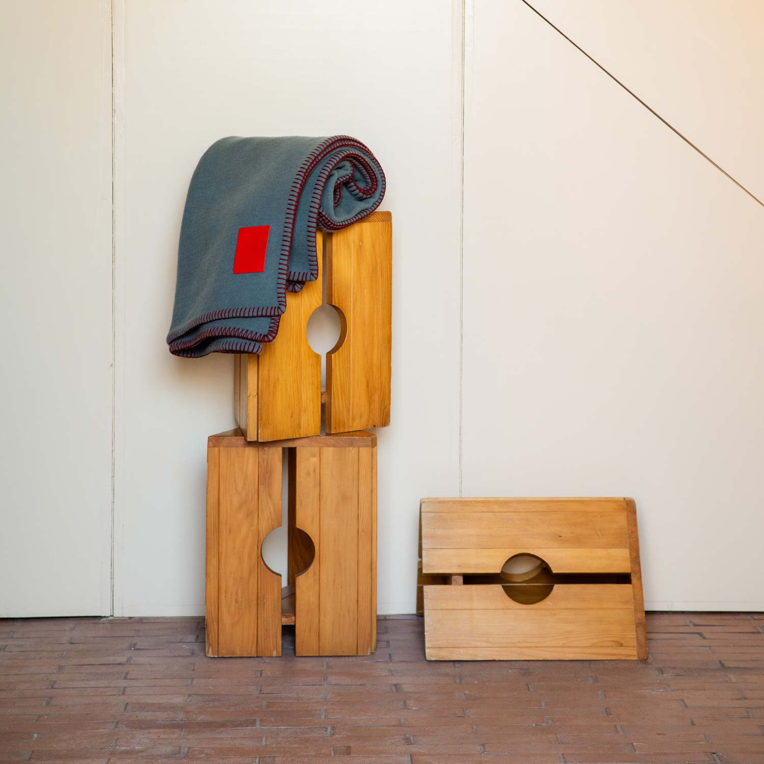 A grey merino blanket draped over some wooden boxes.