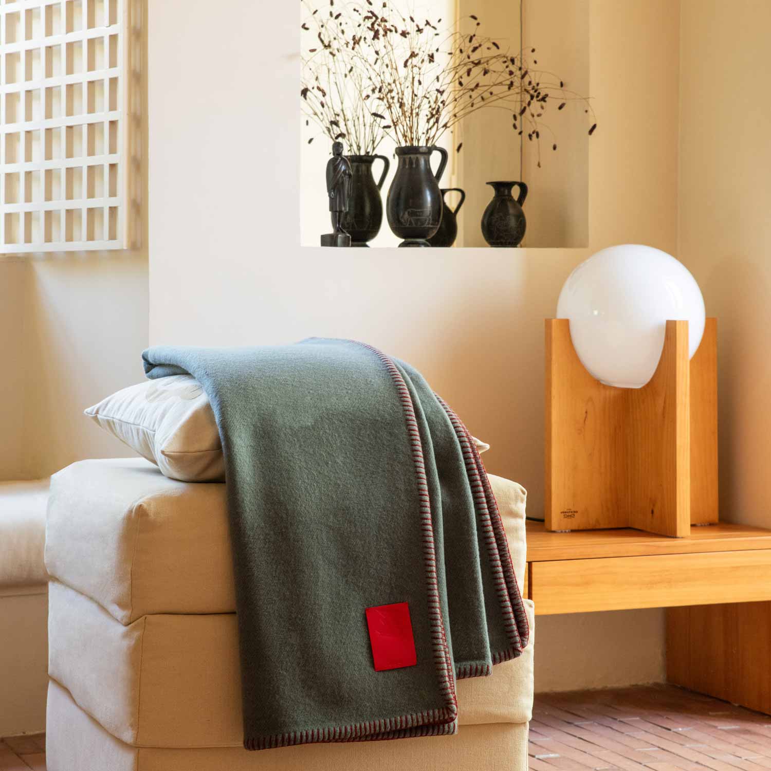 A living room with a table and a sofa, and a grey merino blanket.