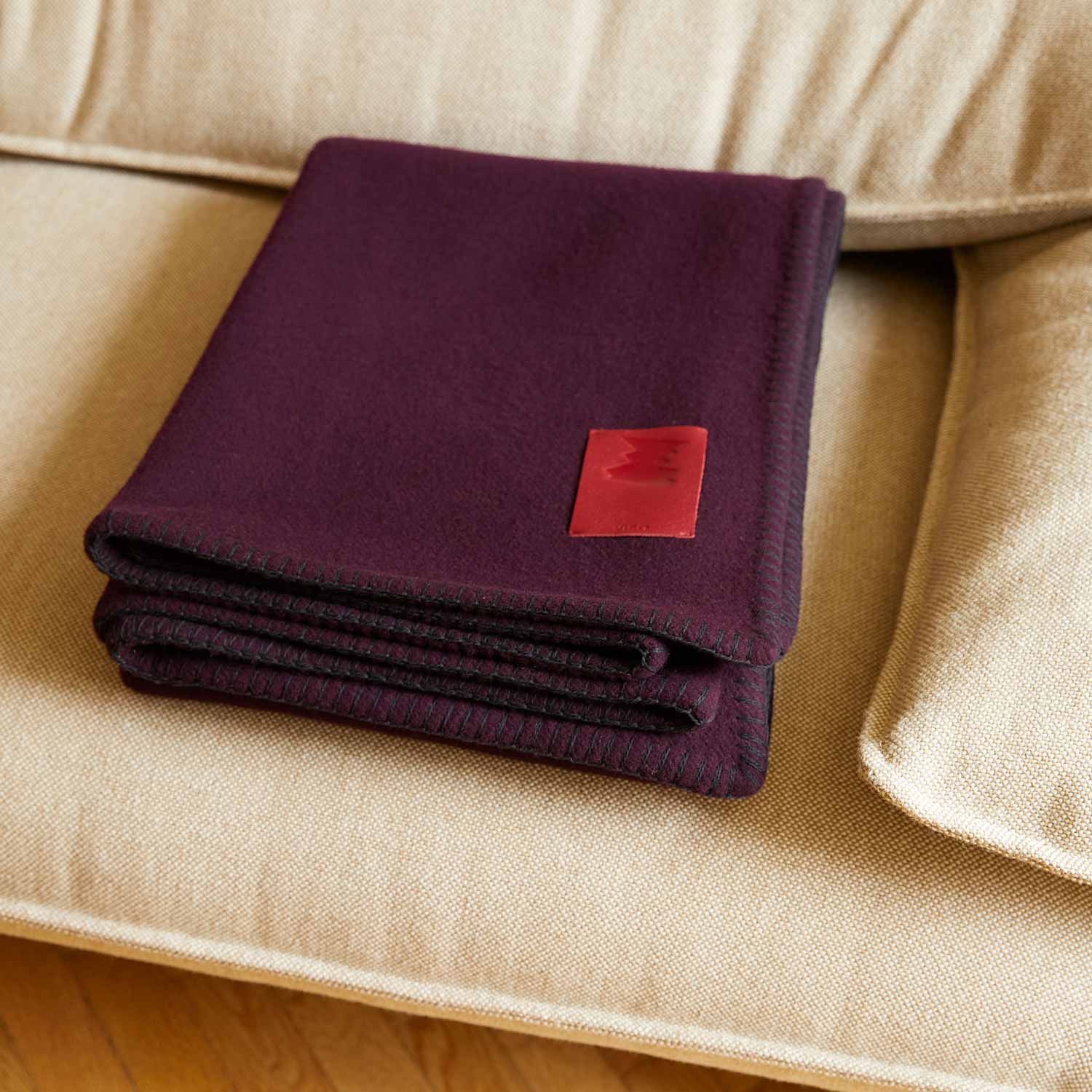 A grey merino blanket on a beige sofa.