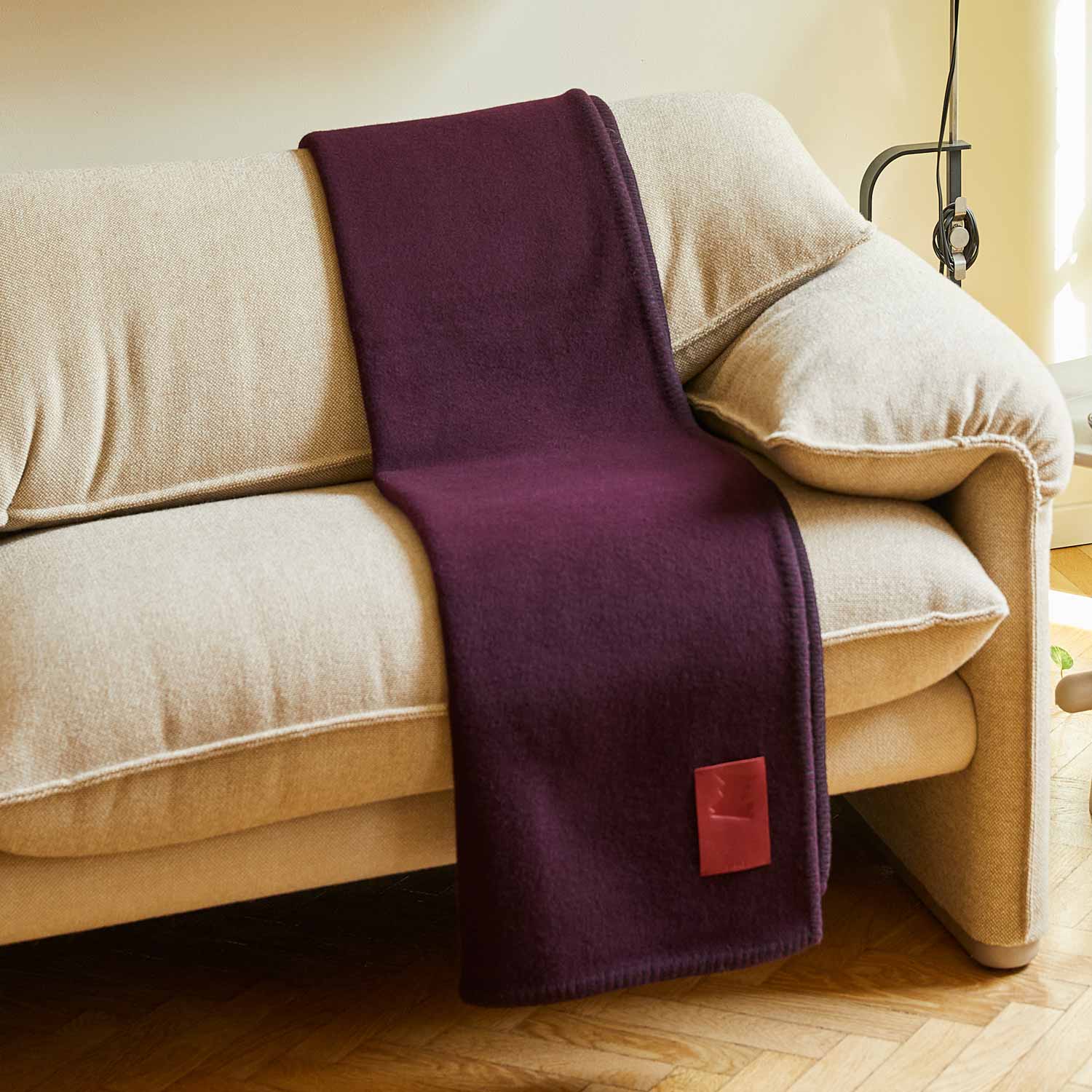 A grey merino blanket on a beige sofa.