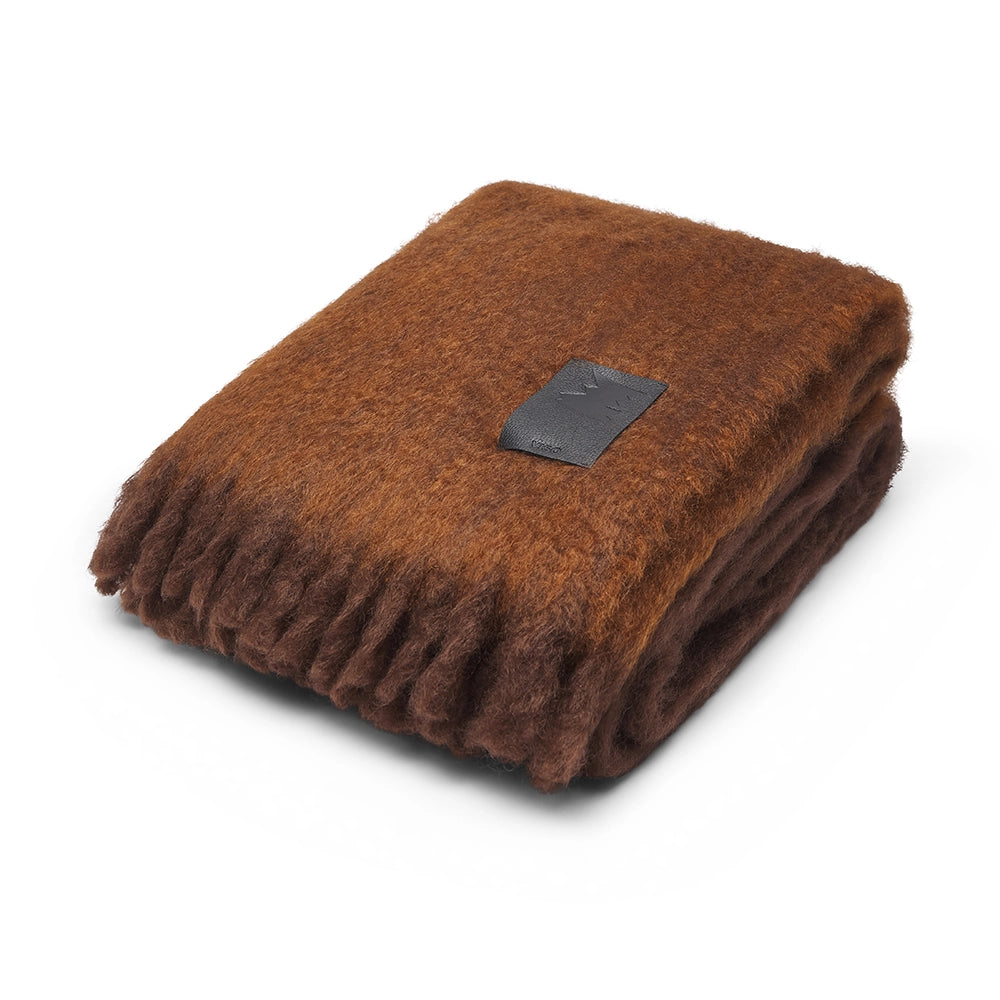 Folded brown mohair blanket with a black label on a white background