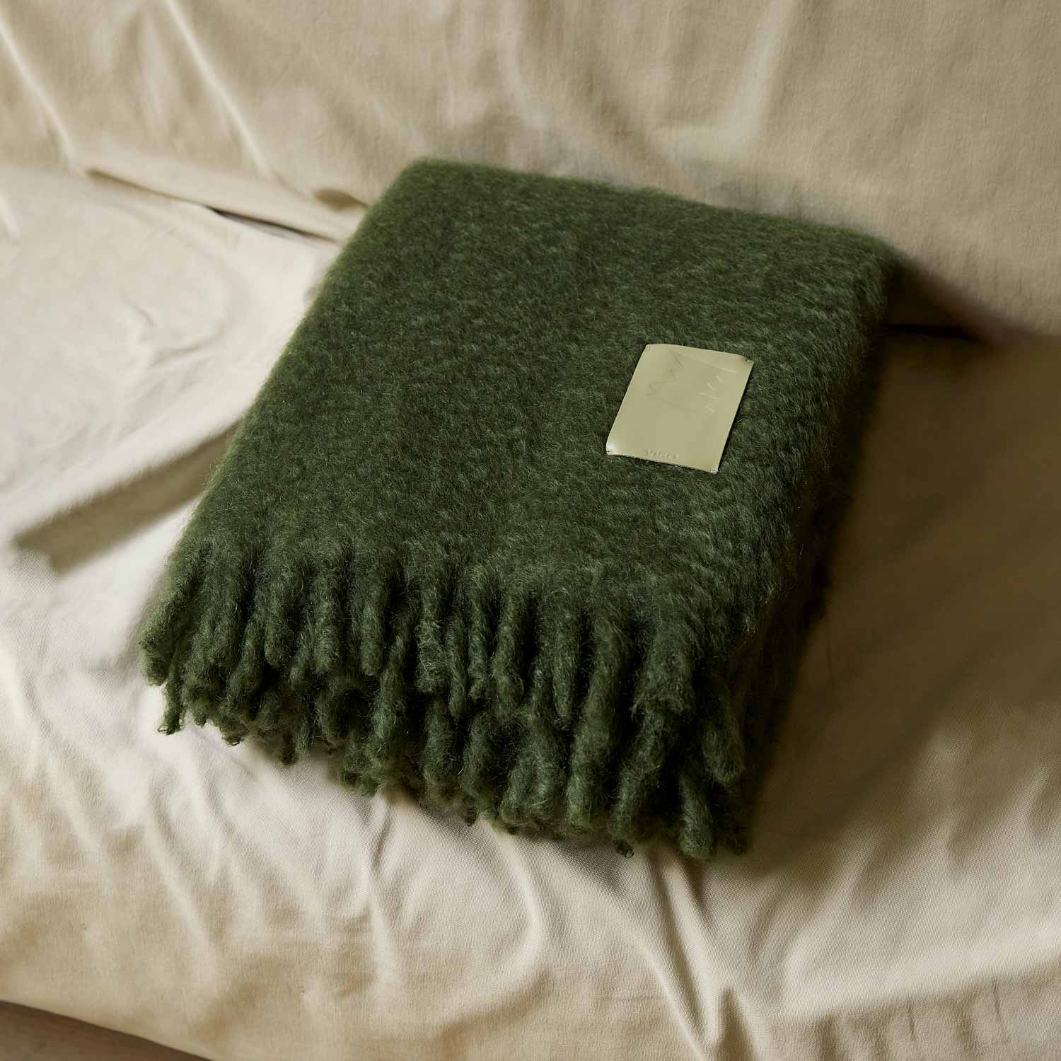 A green mohair blanket on a sofa.