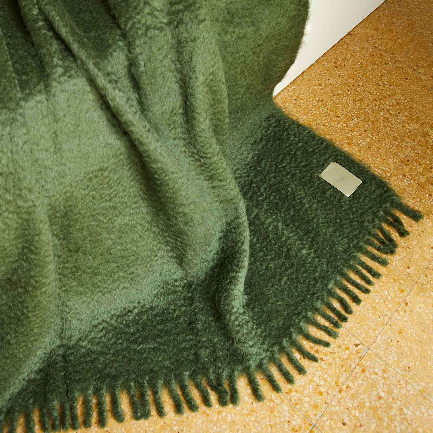 A green mohair blanket draped over a sofa.