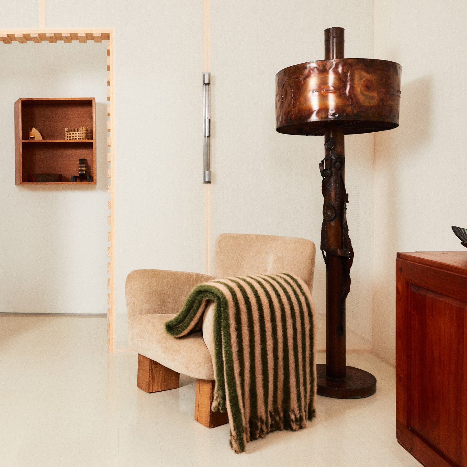 A living room with a mohair blanket draped over an armchair and a floor lamp next to it.