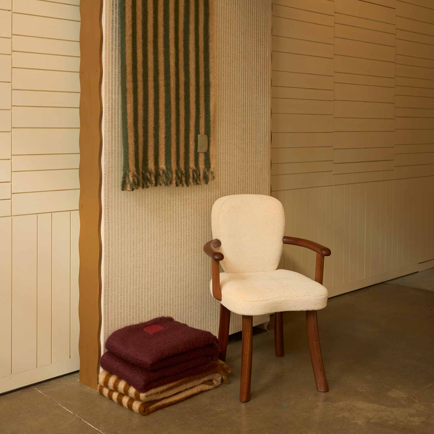 Several mohair blankets share the scene in a living room with a white chair.