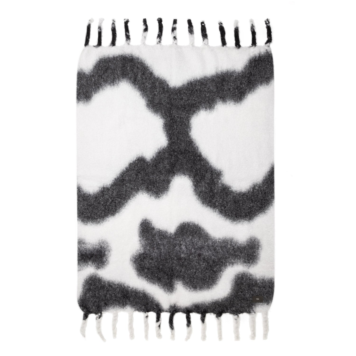 A mohair blanket with a tie-dye pattern in black and white, featuring thick fringes.