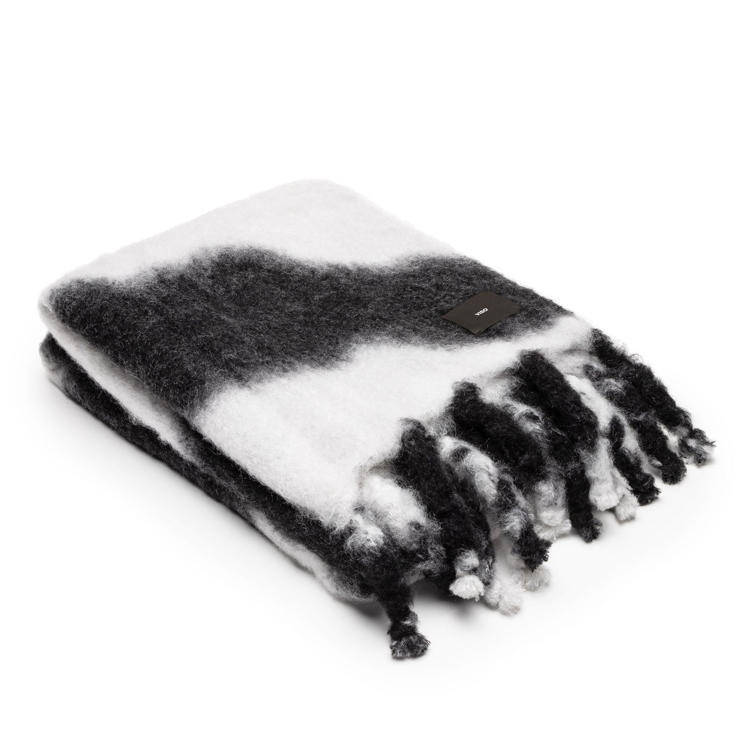 A folded mohair blanket with a tie-dye pattern in black and white, featuring thick fringes.