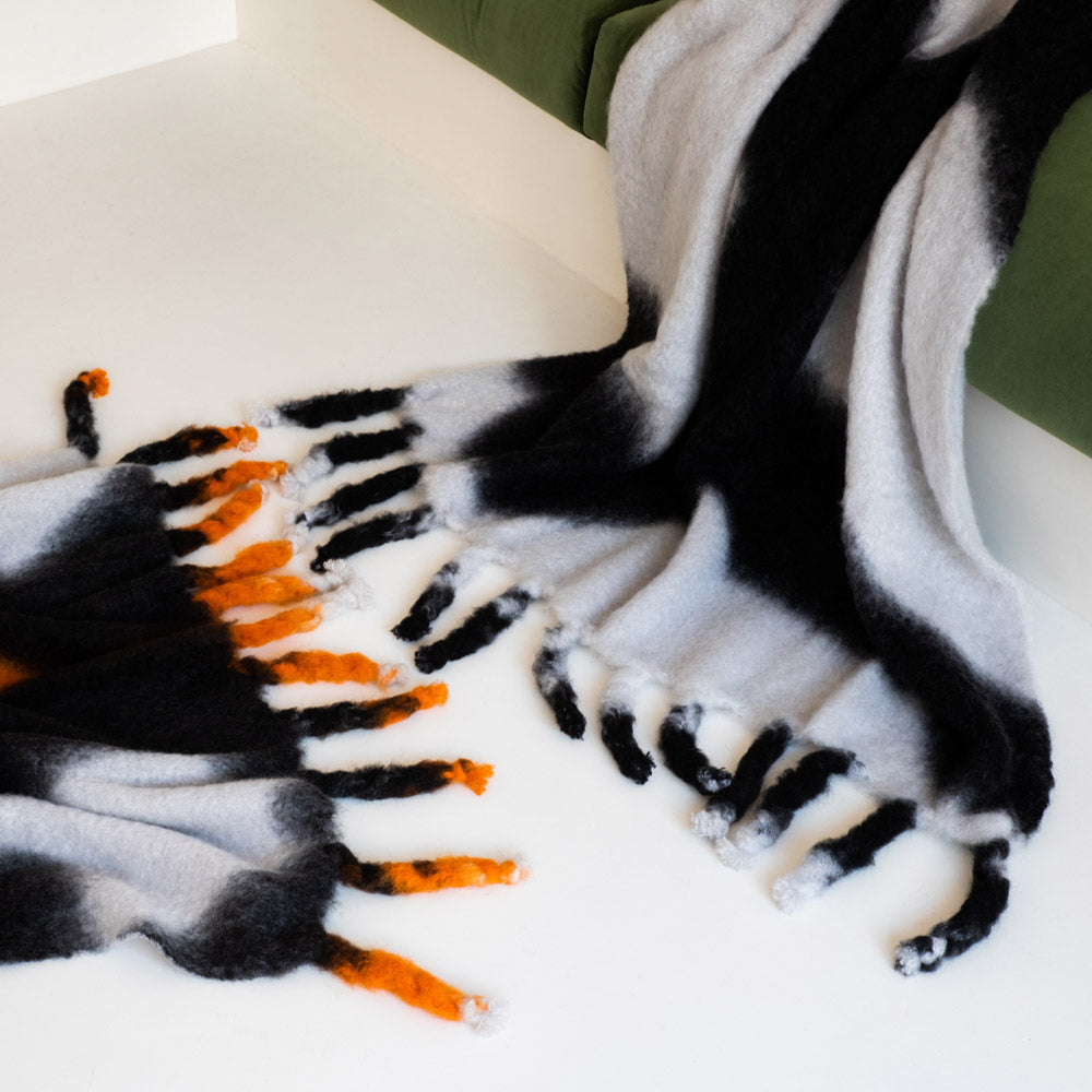A black-and-white tie-dye mohair blanket on a green sofa.