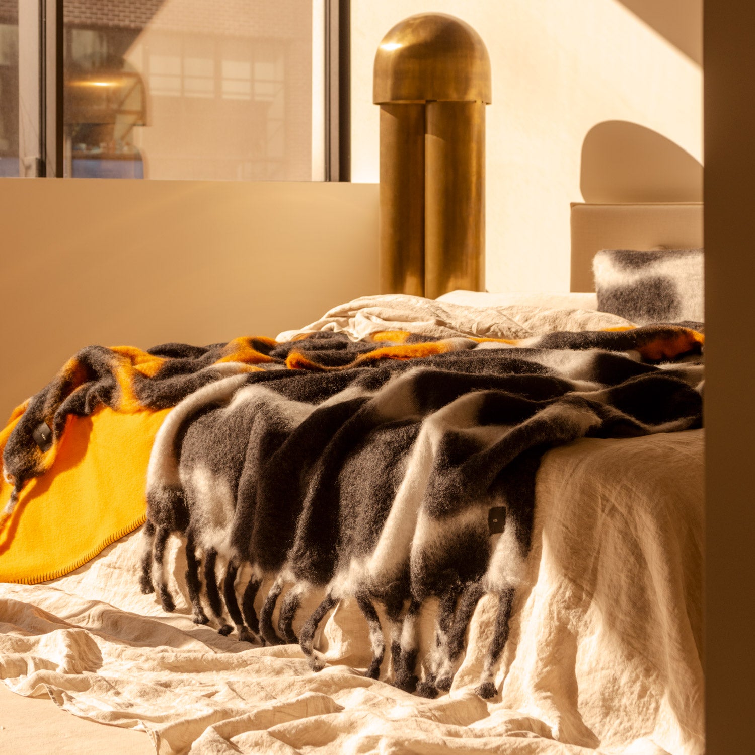 A black-and-white tie-dye mohair blanket on a bed.