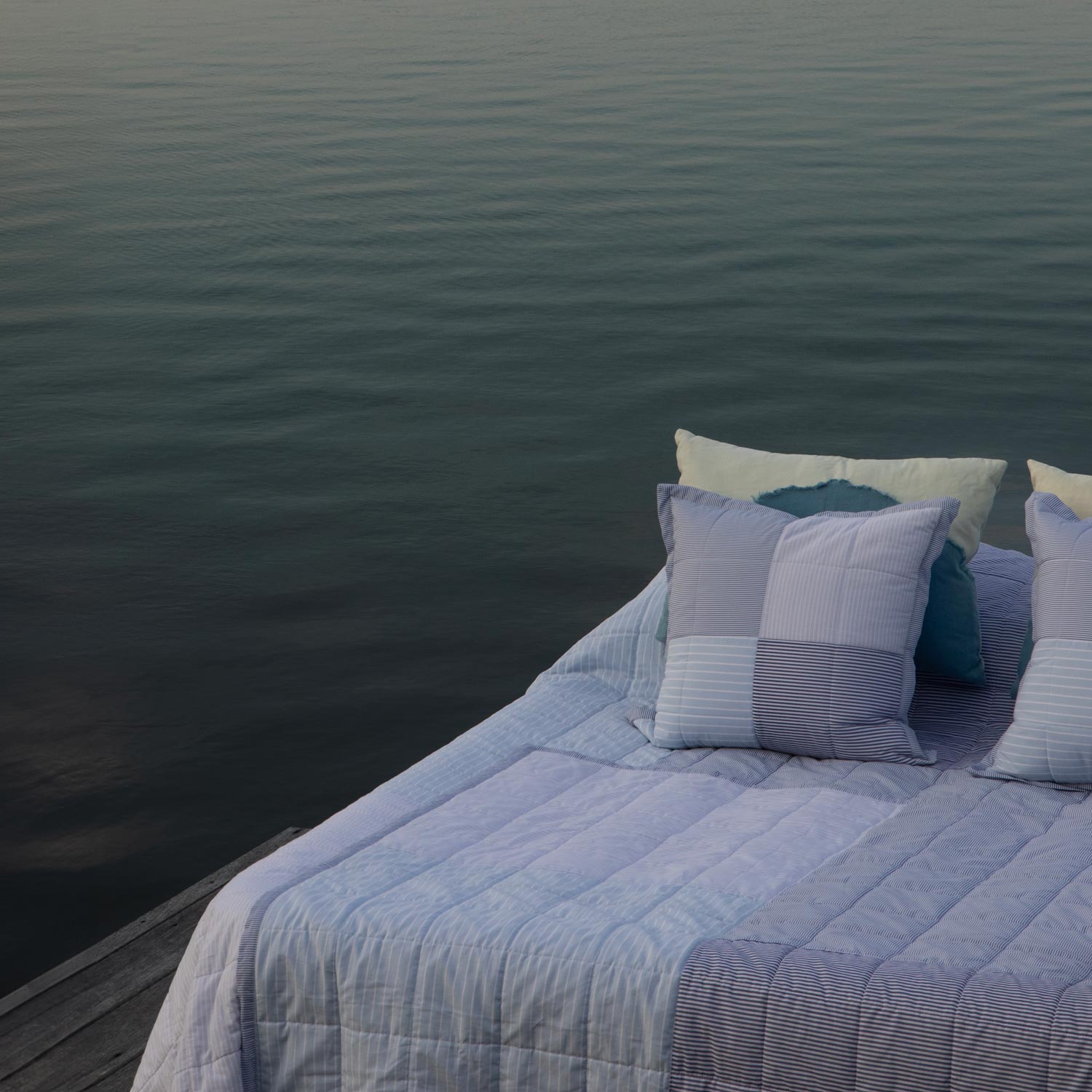 Bed with striped bedding and pillows by a body of water