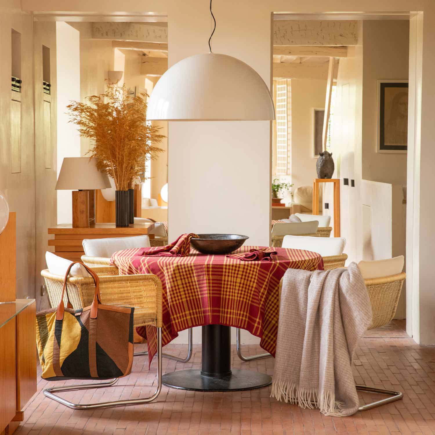 A dining table with a red chequered tablecloth and a blanket draped over one of the chairs.