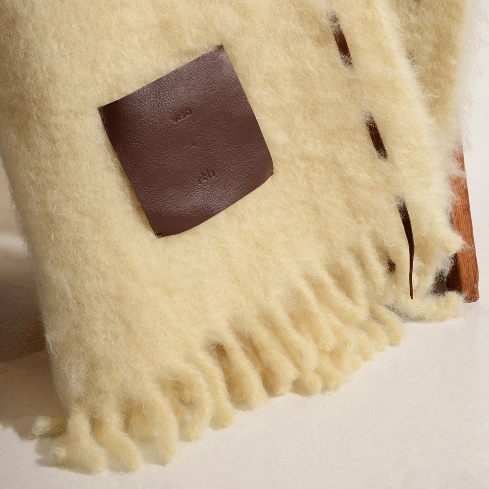Beige blanket with a brown leather patch on a light background