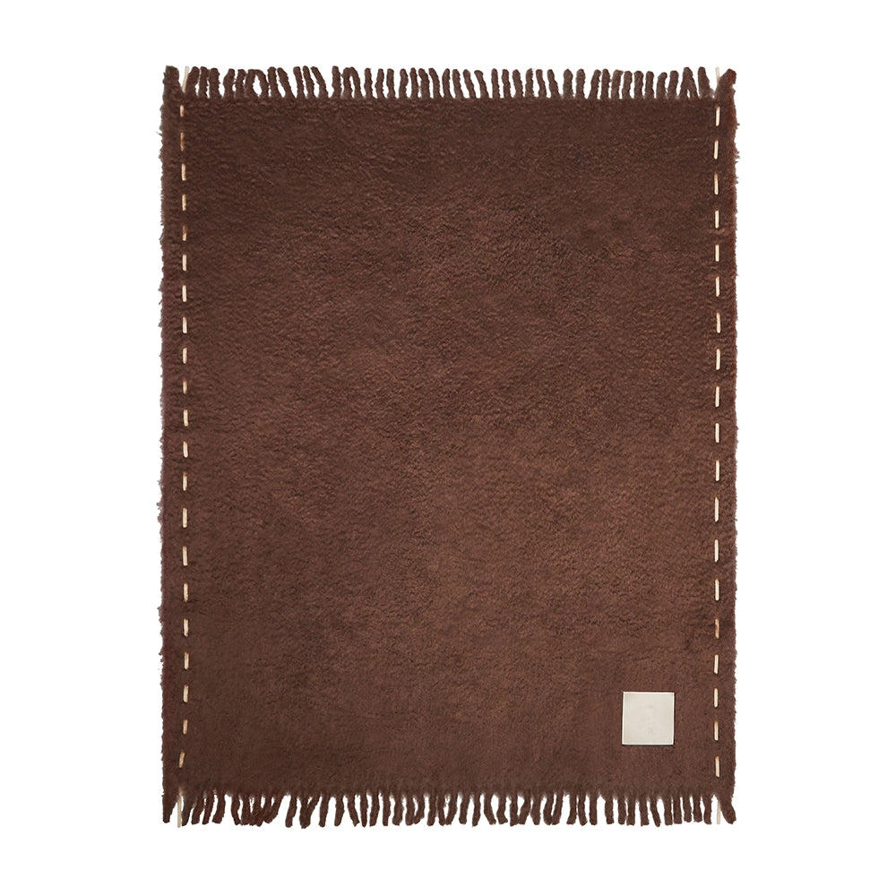 Chocolate woven blanket with cream stitching and a small square label on a white background Ready to Hang X Viso Project