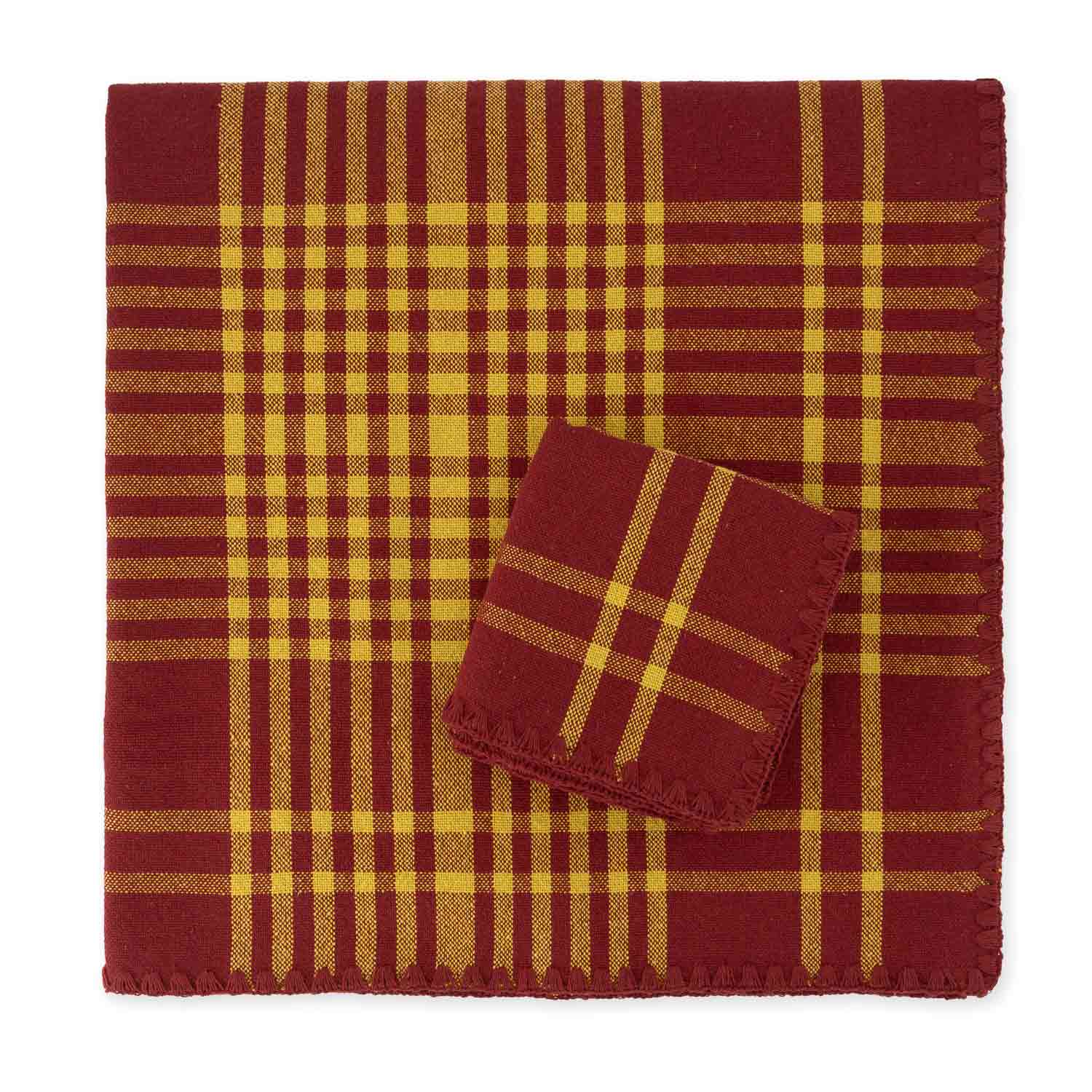 A folded cotton check jacquard tablecloth and napkin featuring a bordeaux and yellow plaid pattern with contrasting detail stitching.