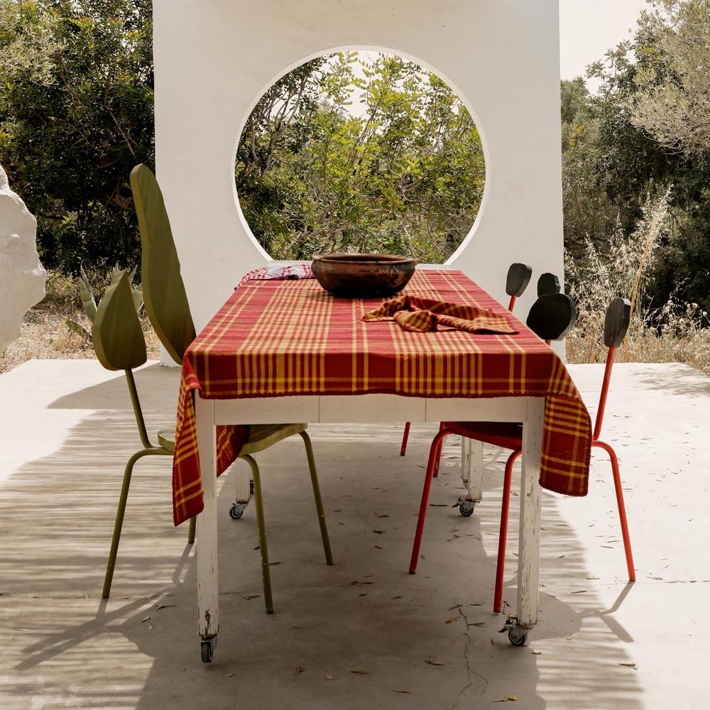 Outdoor dining setup with a table and chairs on a patio, surrounded by greenery.