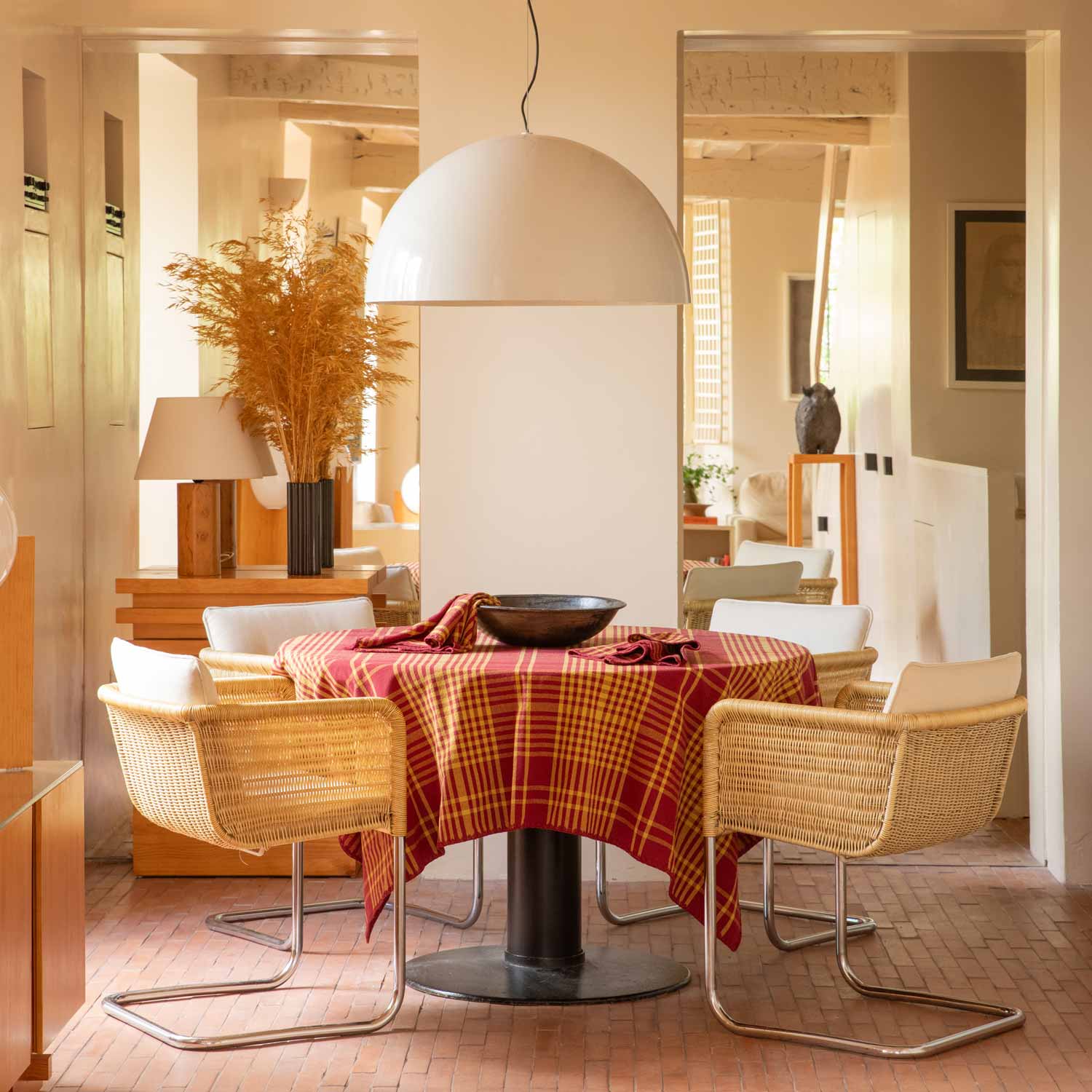 A living room table with some chairs and a table covered with a bordeaux and yellow chequered tablecloth