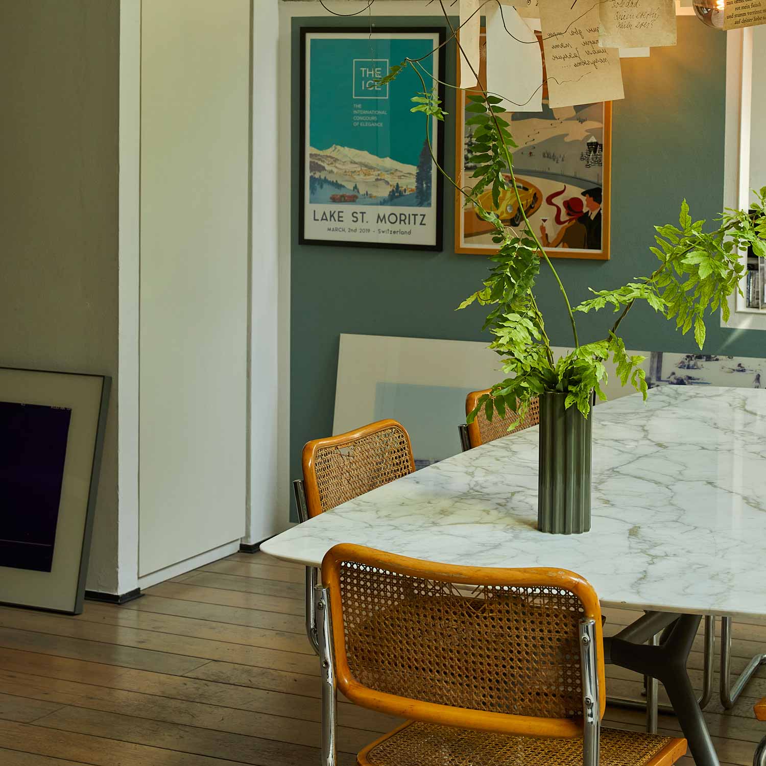 A living room with a marble table and a green ceramic vase.