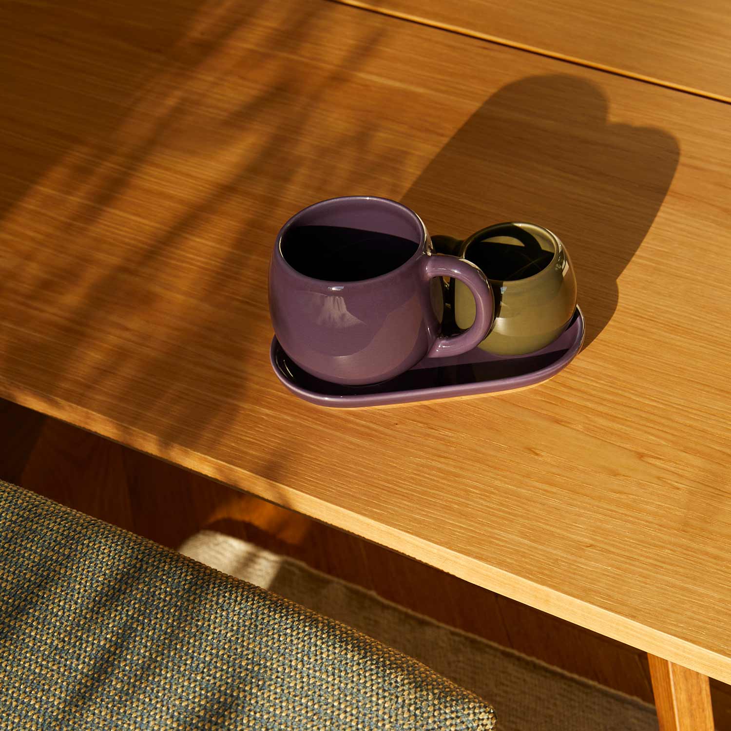 Ceramic cups and a ceramic tray on a wooden table.