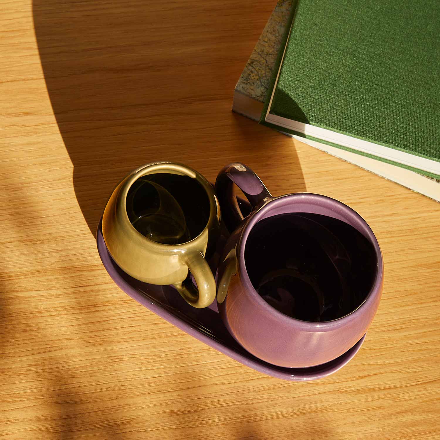Ceramic cups and a ceramic tray on a wooden table.