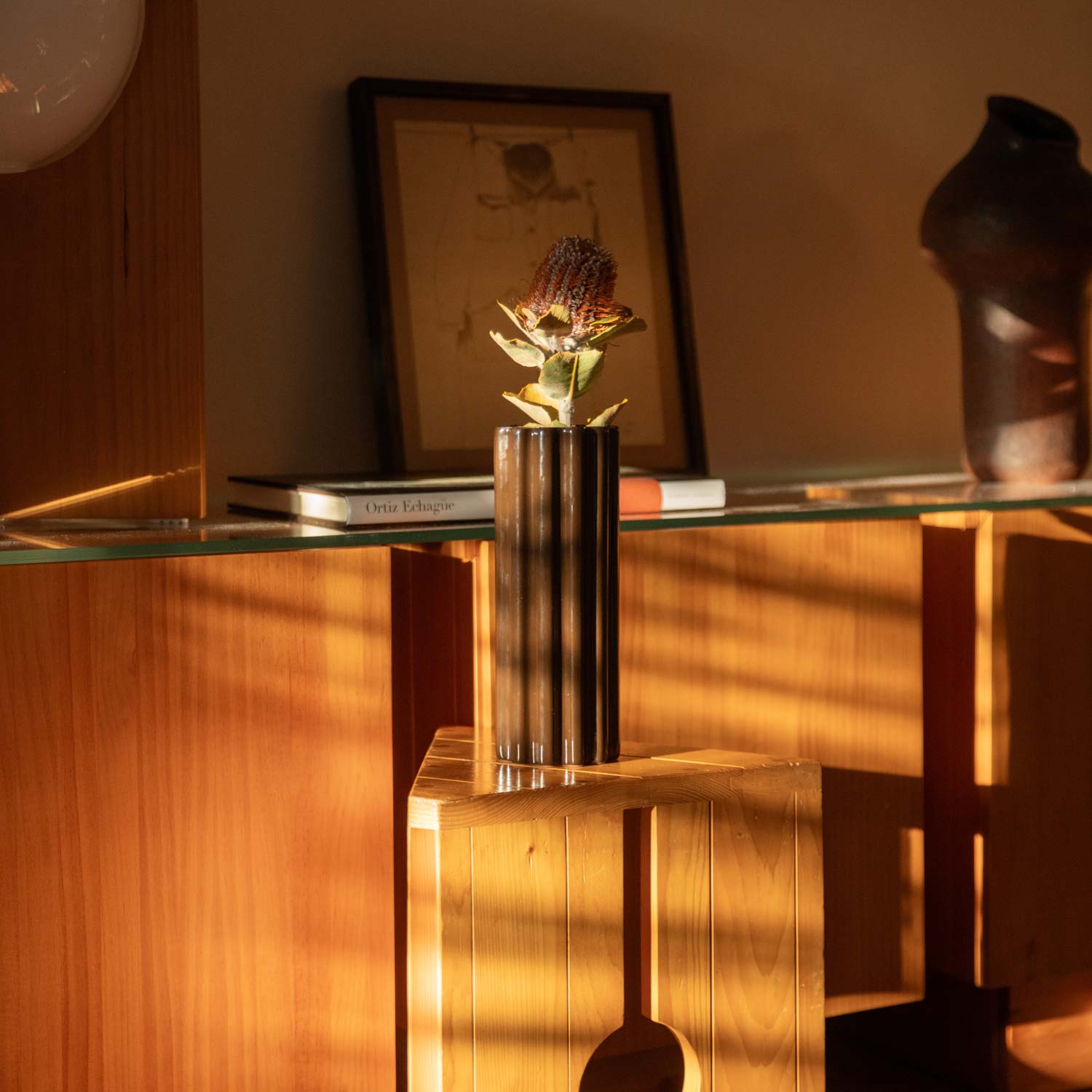 A brown ceramic jar on a wooden table with flowers.