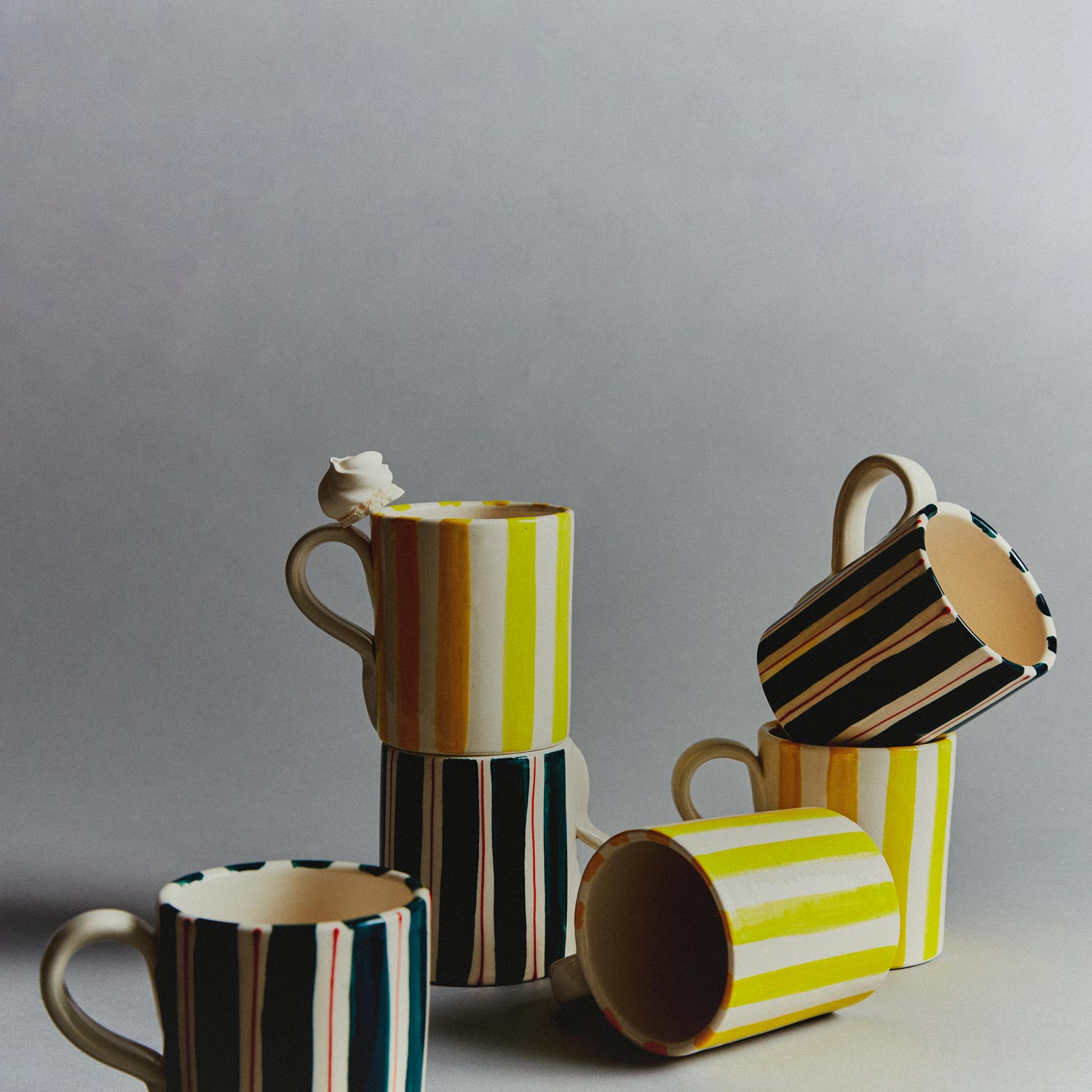 A set of mugs with yellow stripes and others with green and red stripes.