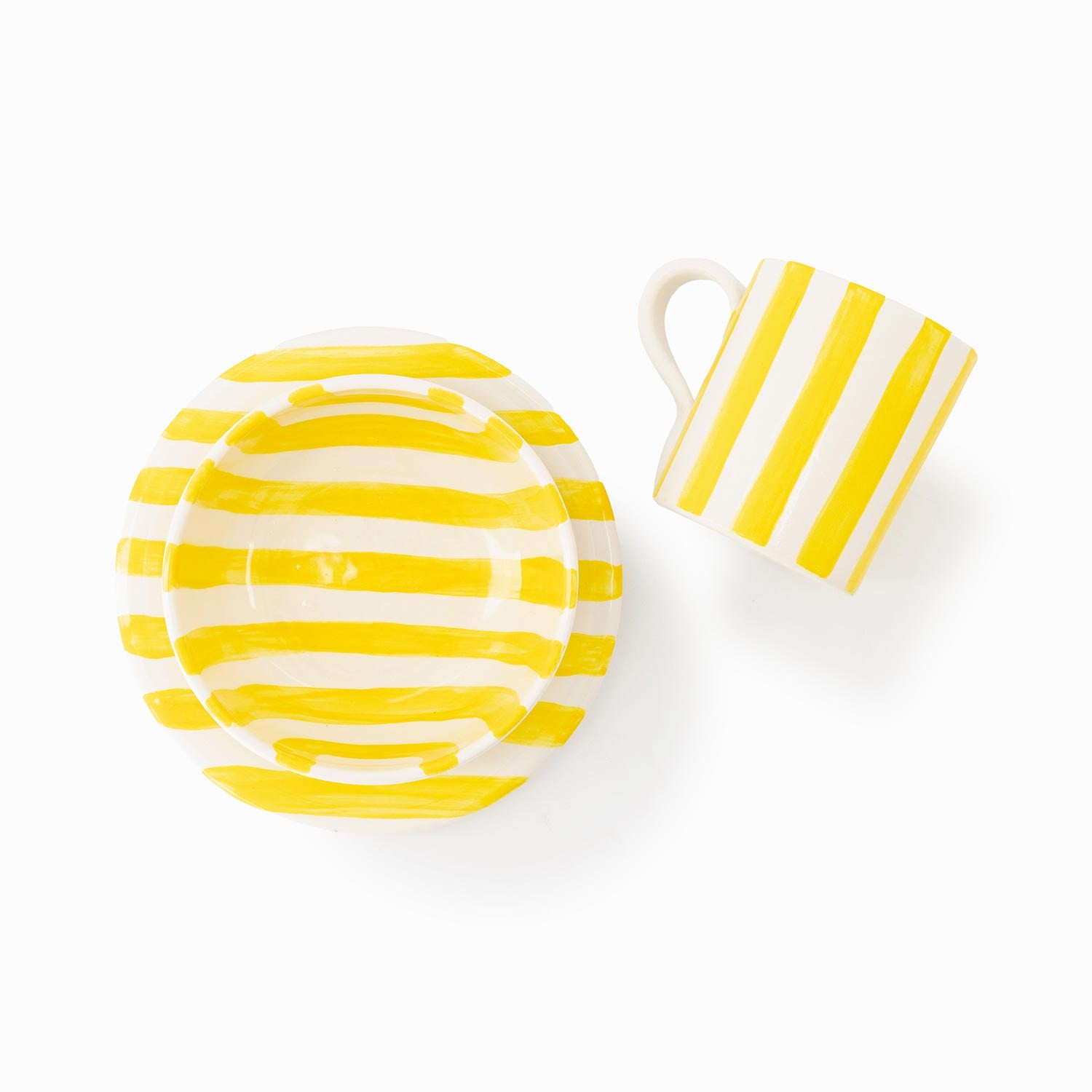 White plate, bowl and mug with yellow stripes on a white background.