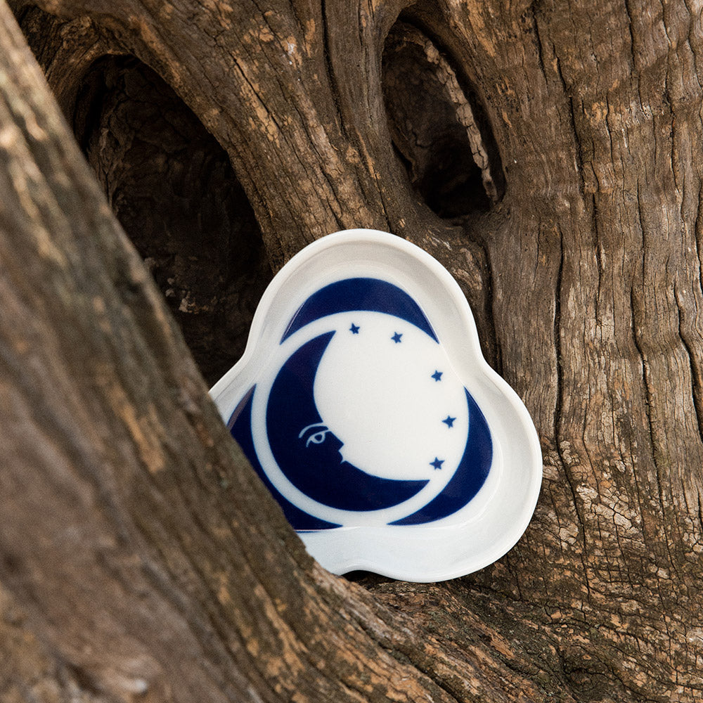 A porcelain tray featuring a design of a moon resting on a tree branch.