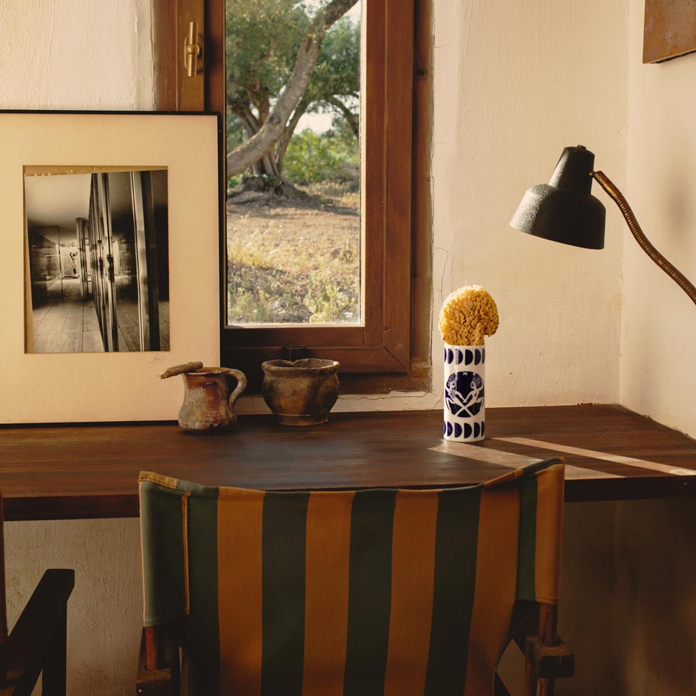 Room interior with a striped chair, table, lamp, and window view.