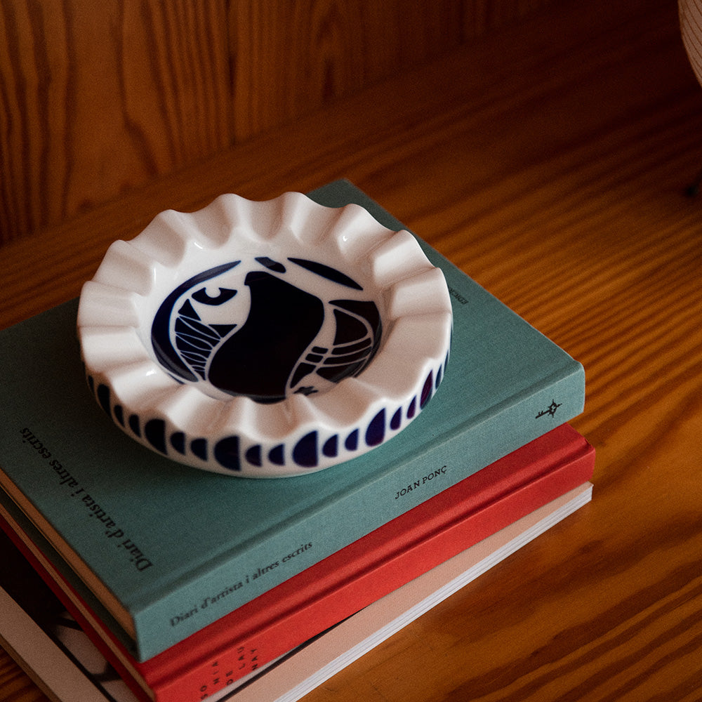 A white and navy porcelain valet tray resting on a surface made up of books.