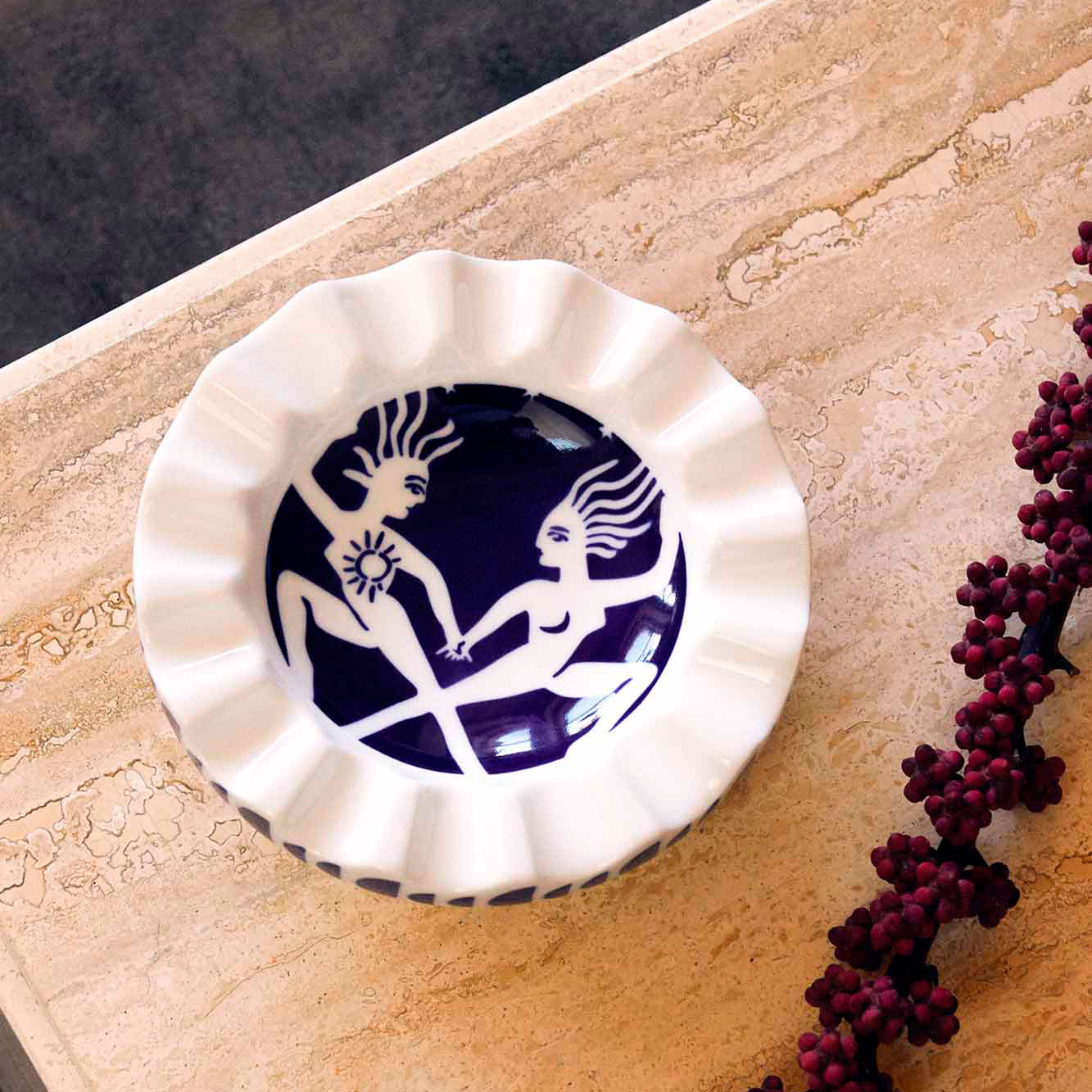 A white and navy porcelain valet tray, set on a base and decorated with flowers.