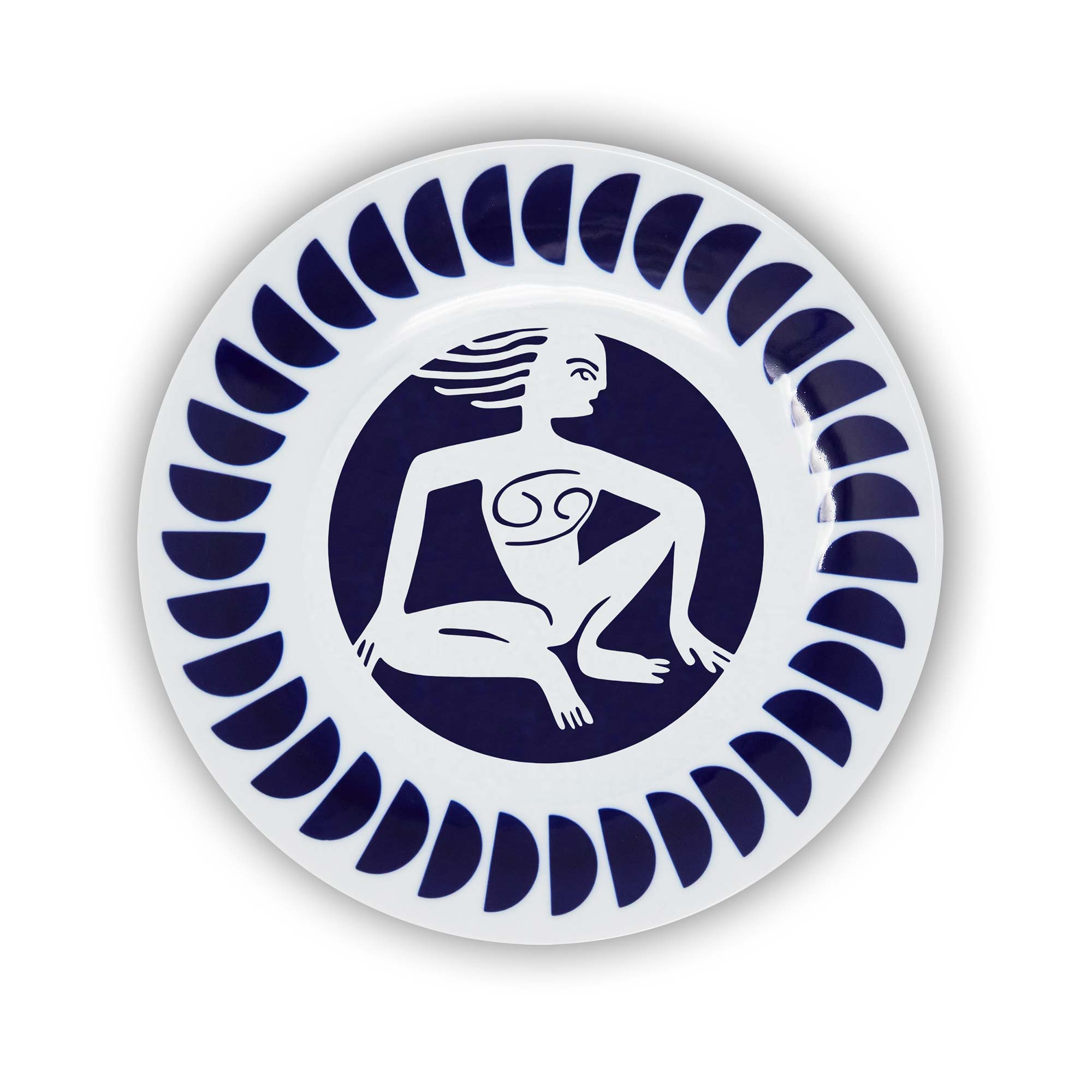 A round porcelain plate with a navy and white design featuring an illustration of the Cancer sign of the zodiac.