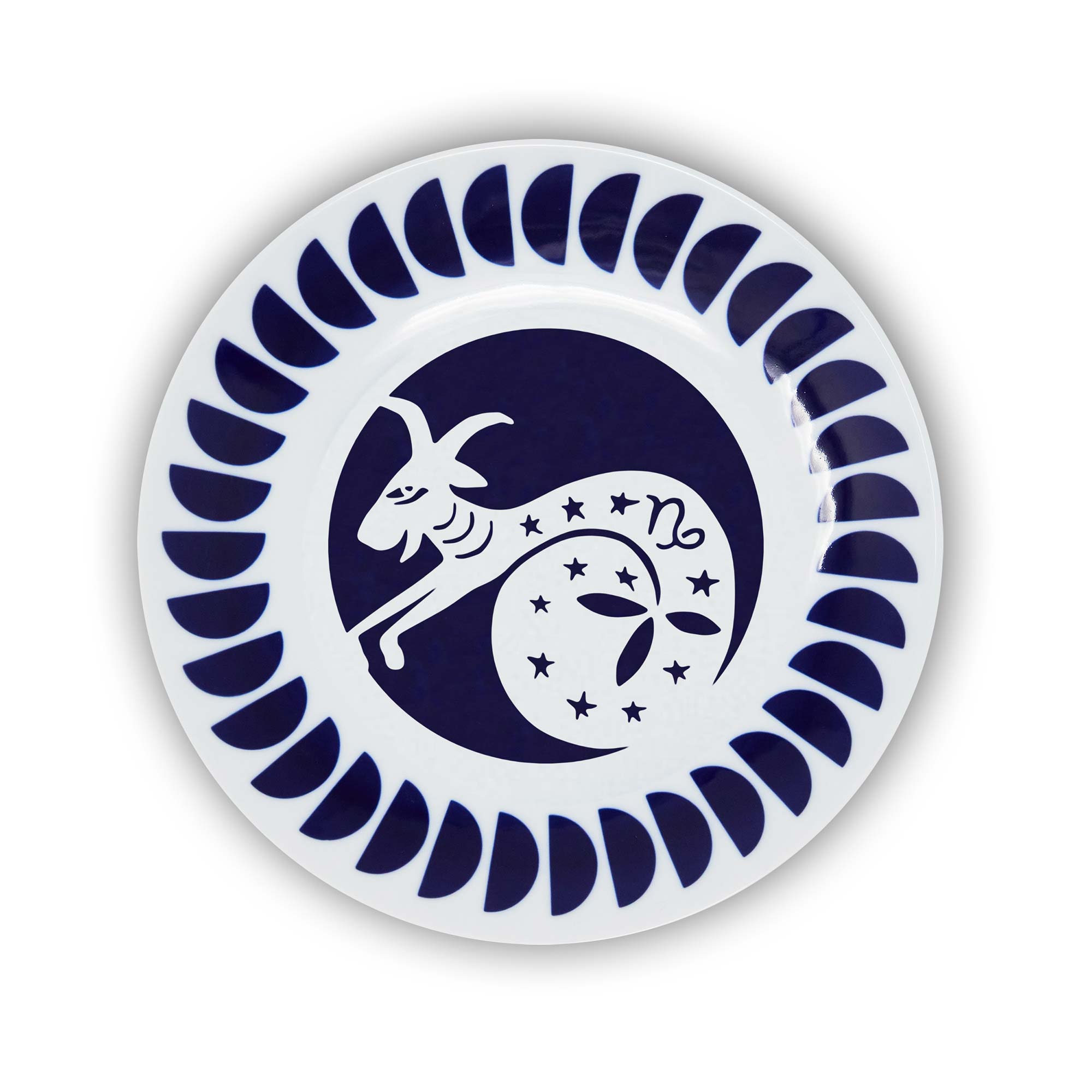 A round porcelain plate with a navy and white design featuring an illustration of the Capricorn sign of the zodiac.