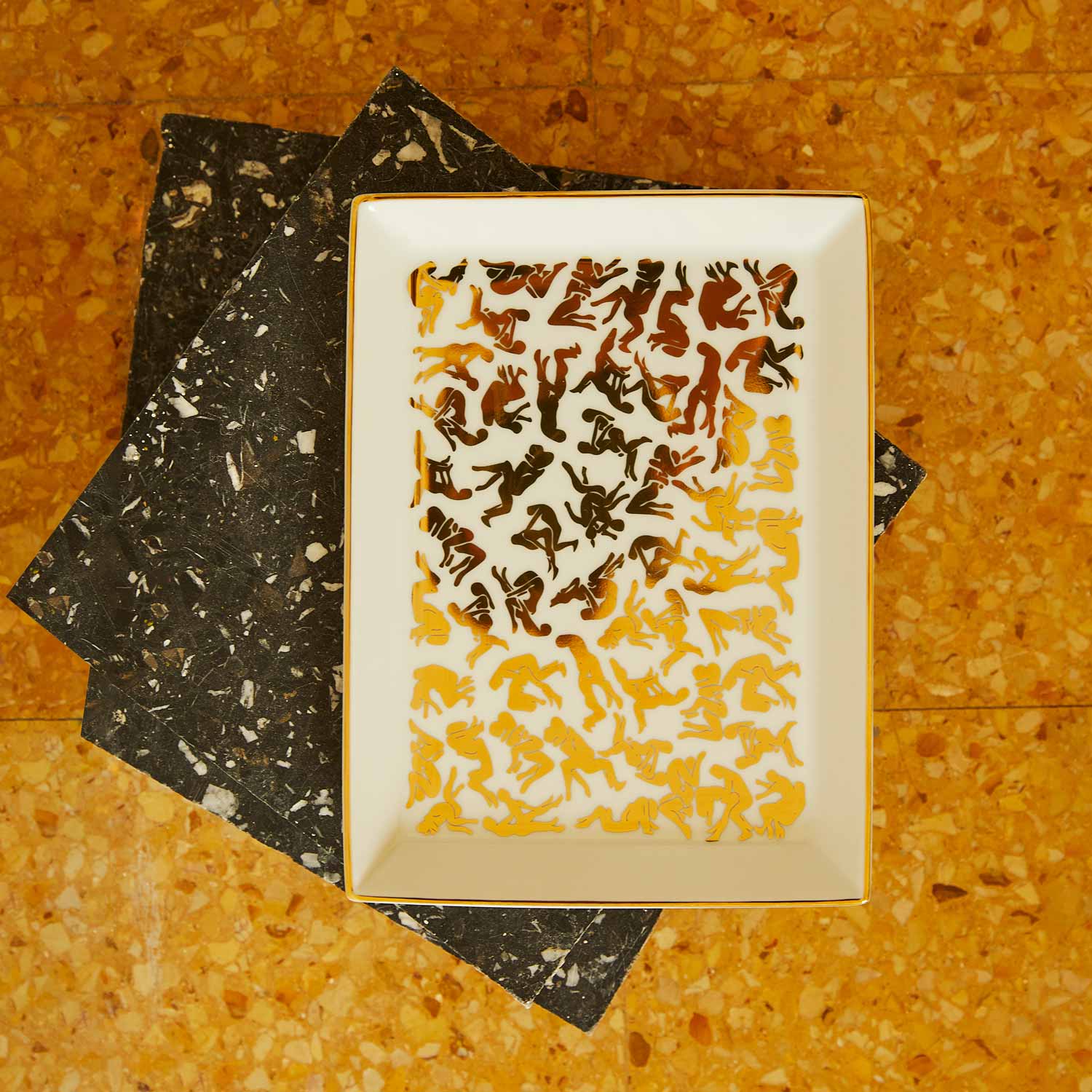 A white porcelain tray featuring a pattern of Kamasutra positions on various pieces of marble.