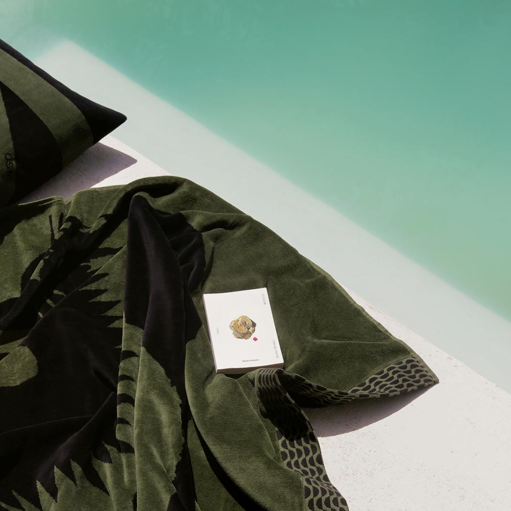 Green towel with a brand logo on a white surface with a green background