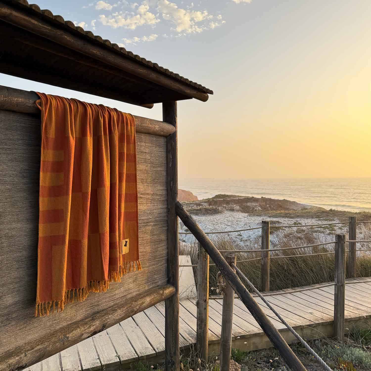 Orange striped towel hanging on a wooden railing with a scenic ocean view.