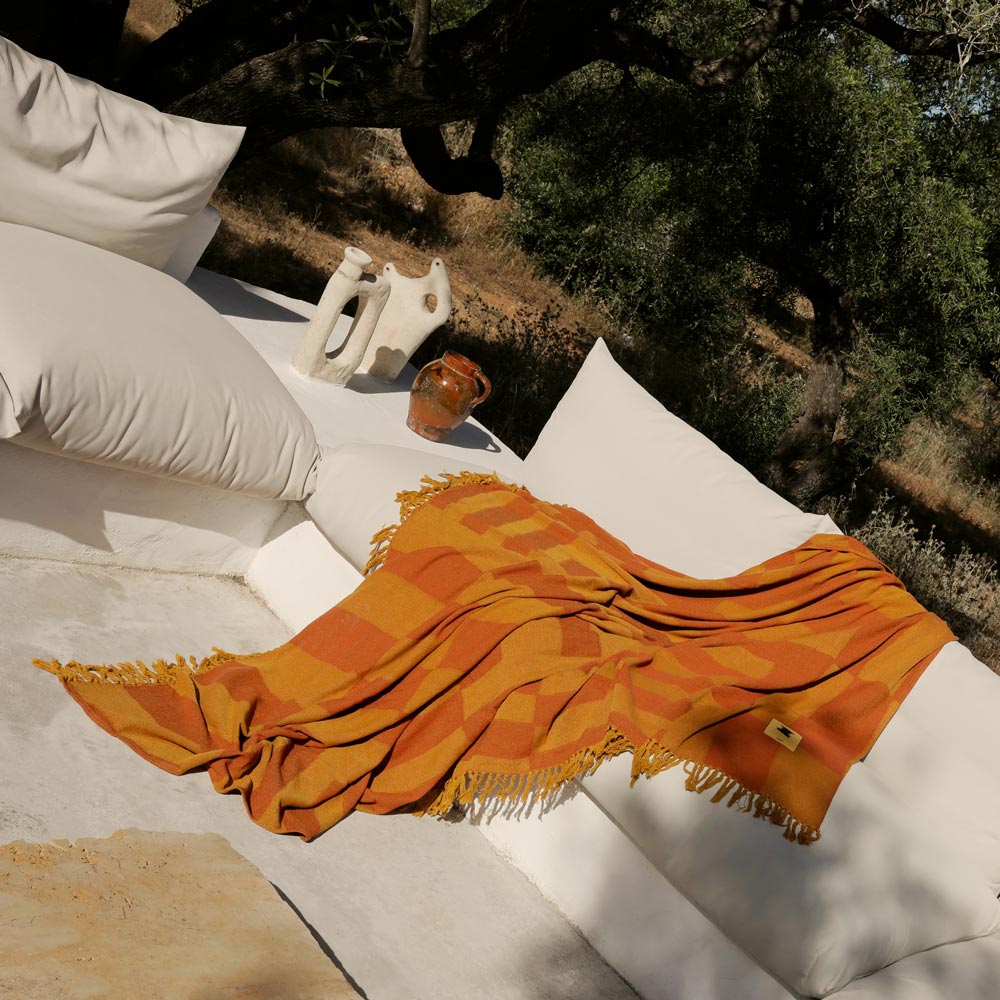 Orange checkered towel on a white outdoor sofa with a natural background