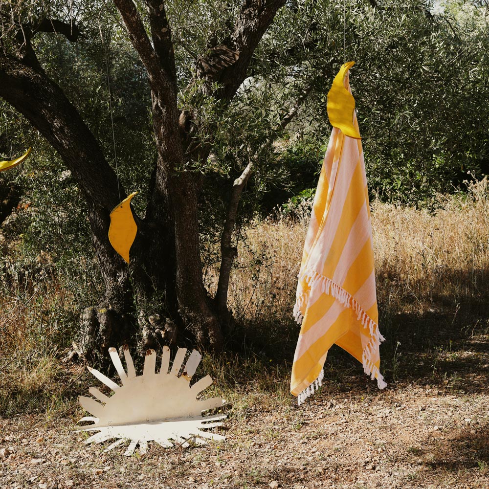 Yellow and white striped towel hanging from a tree in a natural setting