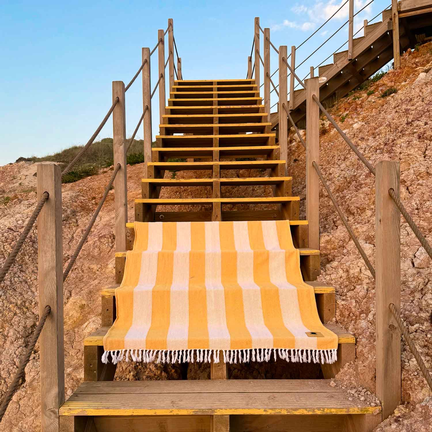 Yellow and white striped towel on a wooden staircase with a rocky cliff background