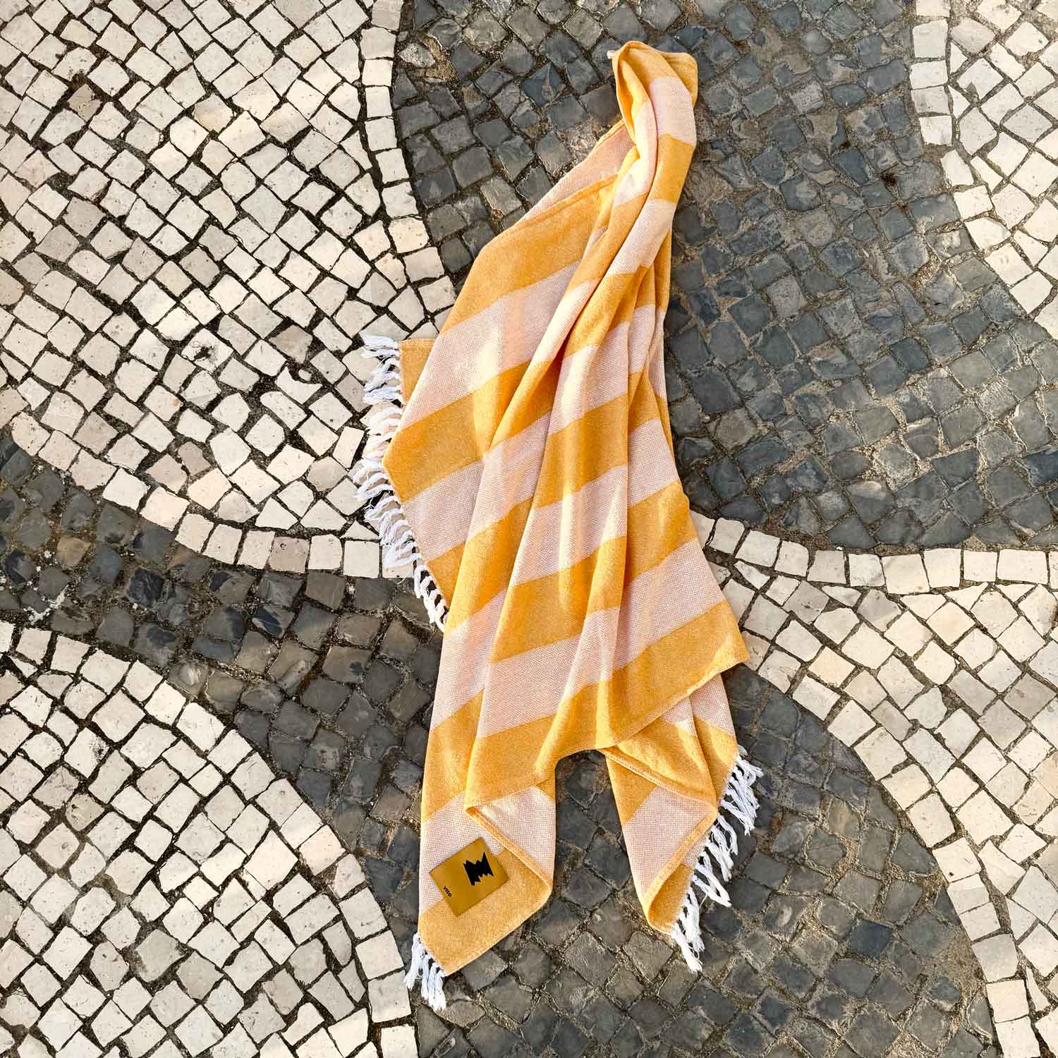 Yellow and white striped towel on a stone pavement