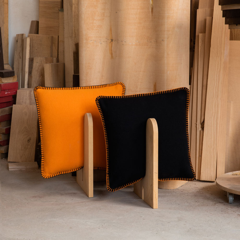 An orange and black merino pillow in a studio.