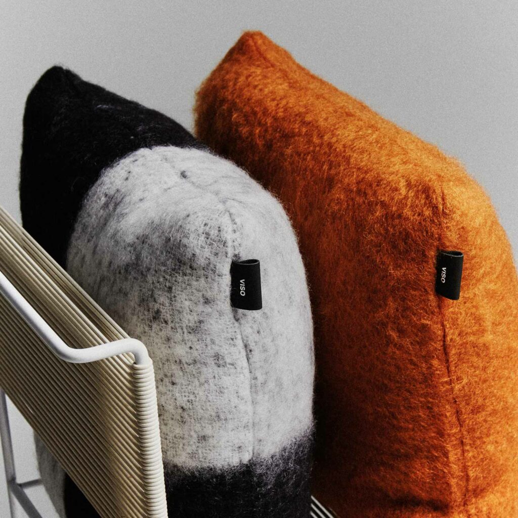 A close-up of a black-and-white checkered pillow and a brown pillow, both on a chair.