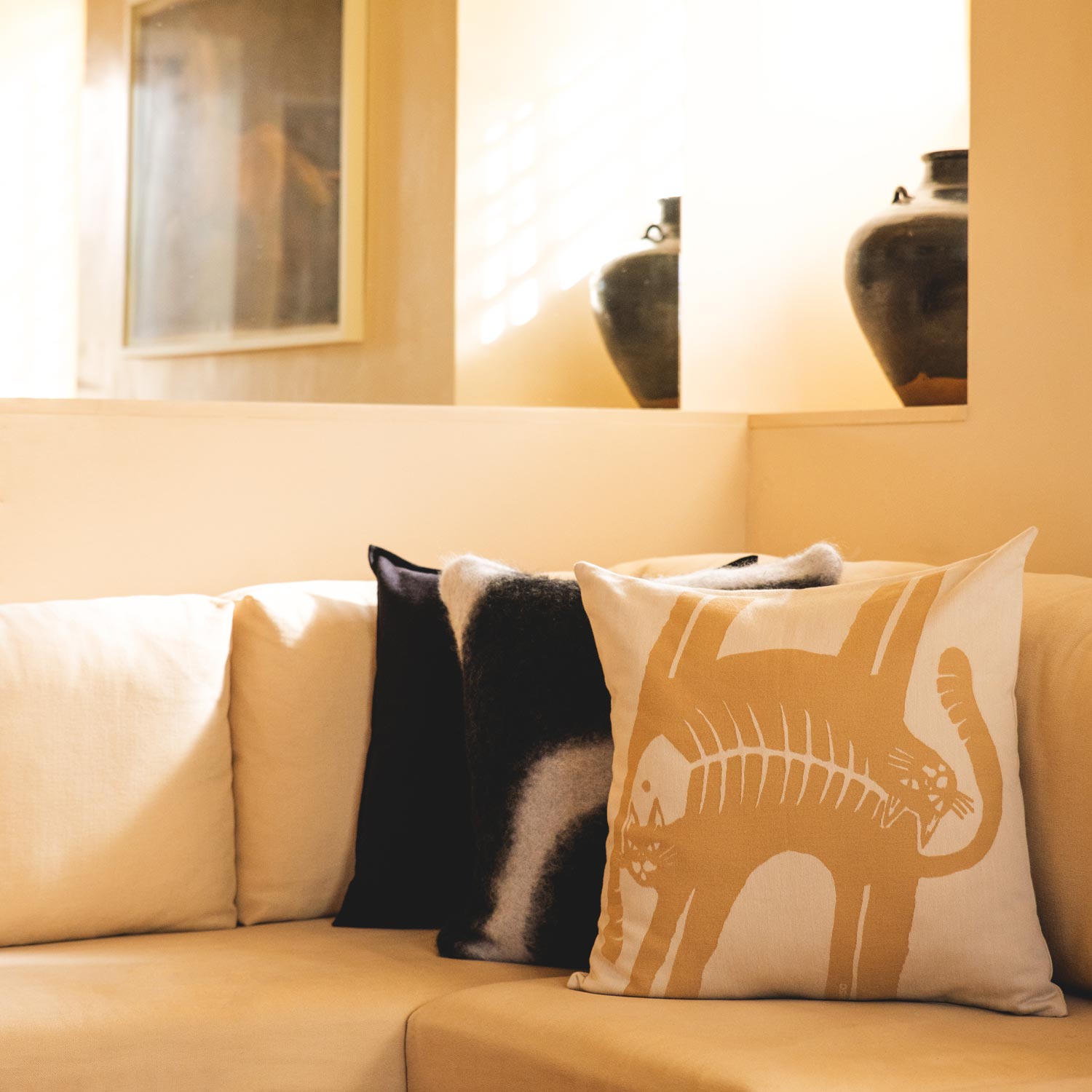 A living room with a cream-coloured sofa and a selection of pillows.