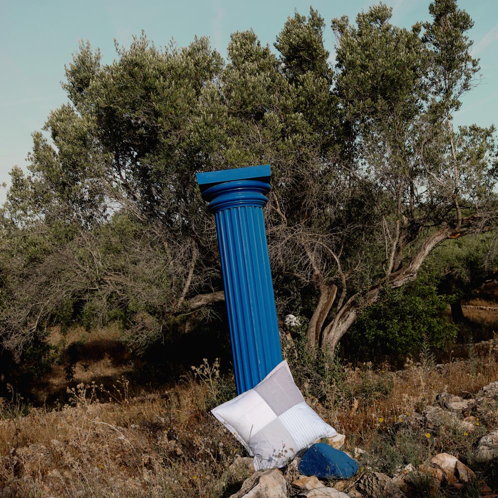 Blue column with a checkered pillow in a natural setting