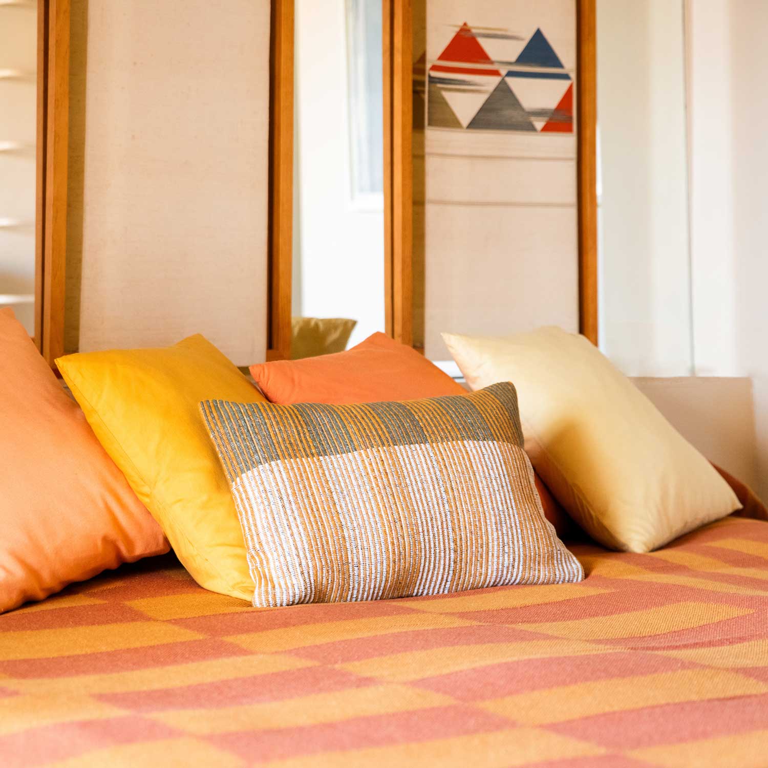 Close-up of pillows in shades of ochre and yellow on a bed