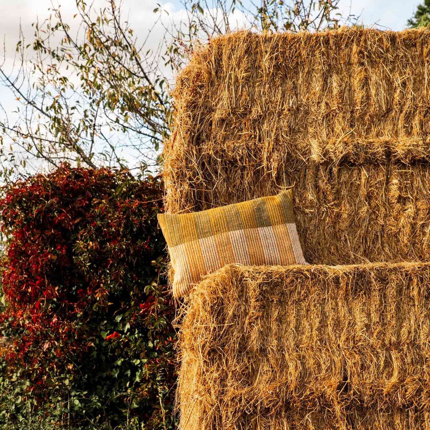 A yellow pillow on a bale of straw in the countryside
