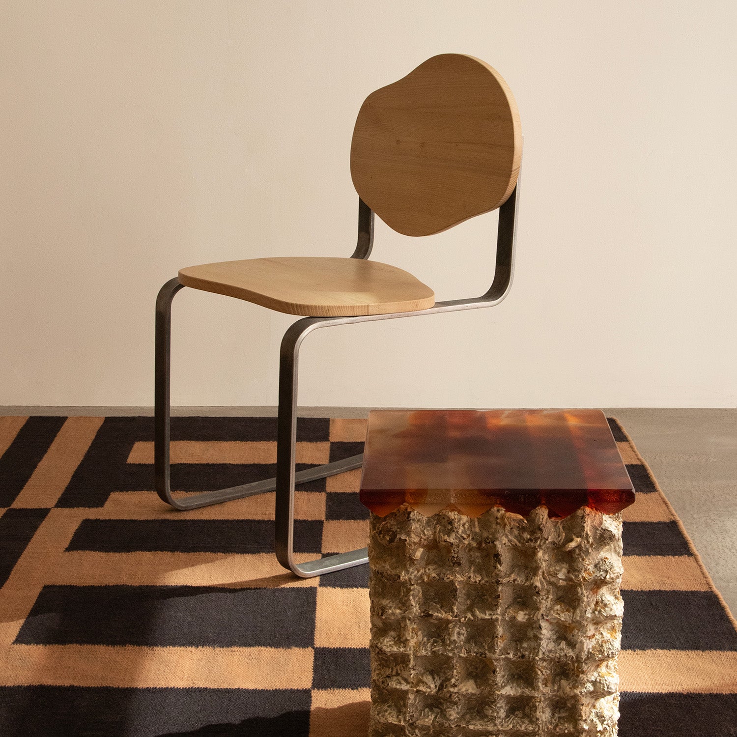 Modern chair with a wooden seat and backrest, metal frame, and textured table on a patterned rug.