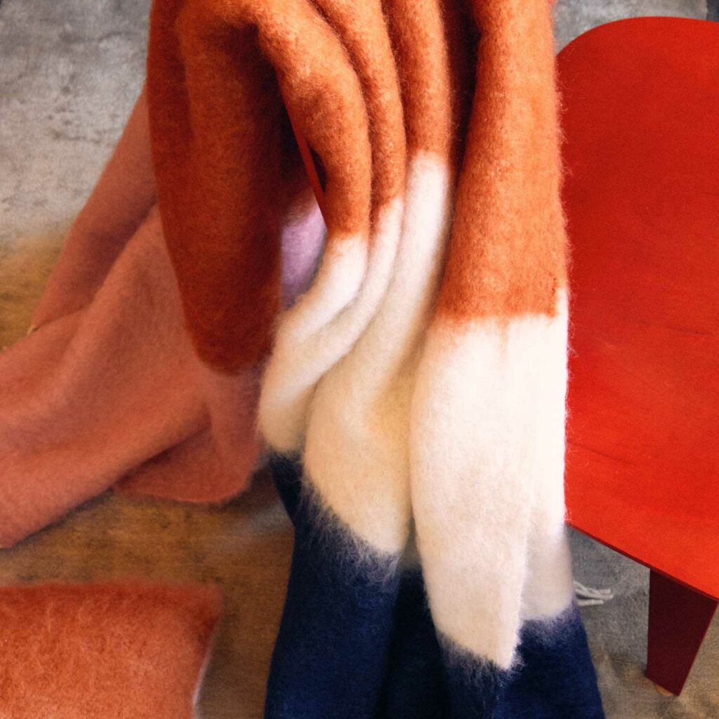 Pink, orange, white and navy mohair blanket resting on a chair